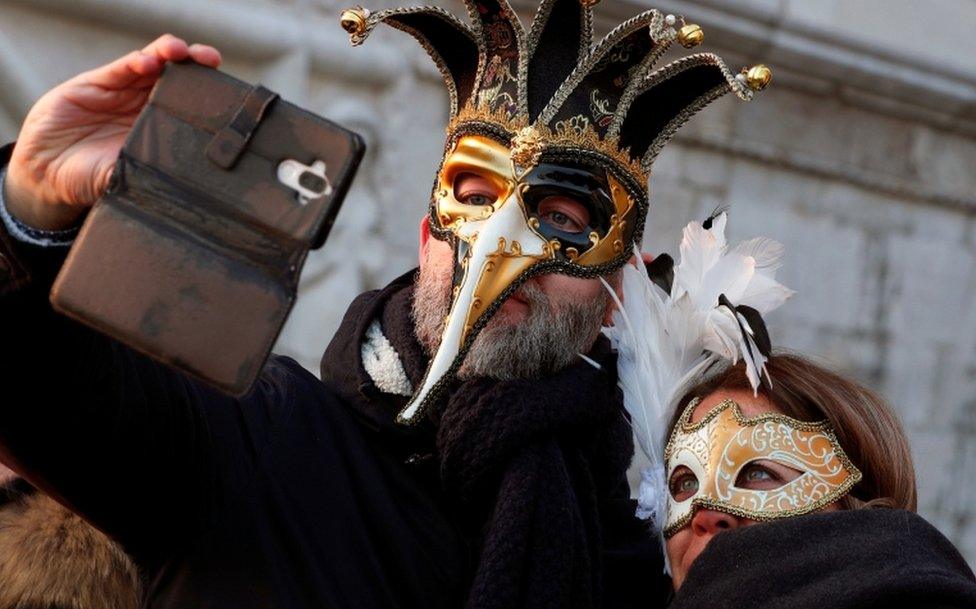 A masked couple takes a selfie during Carnival celebrations