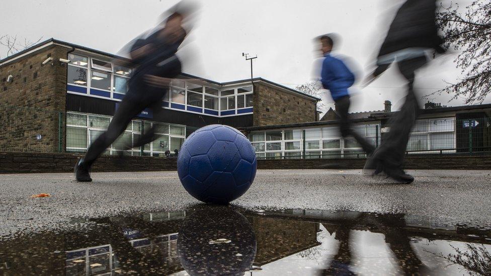 Children kicking ball in playground