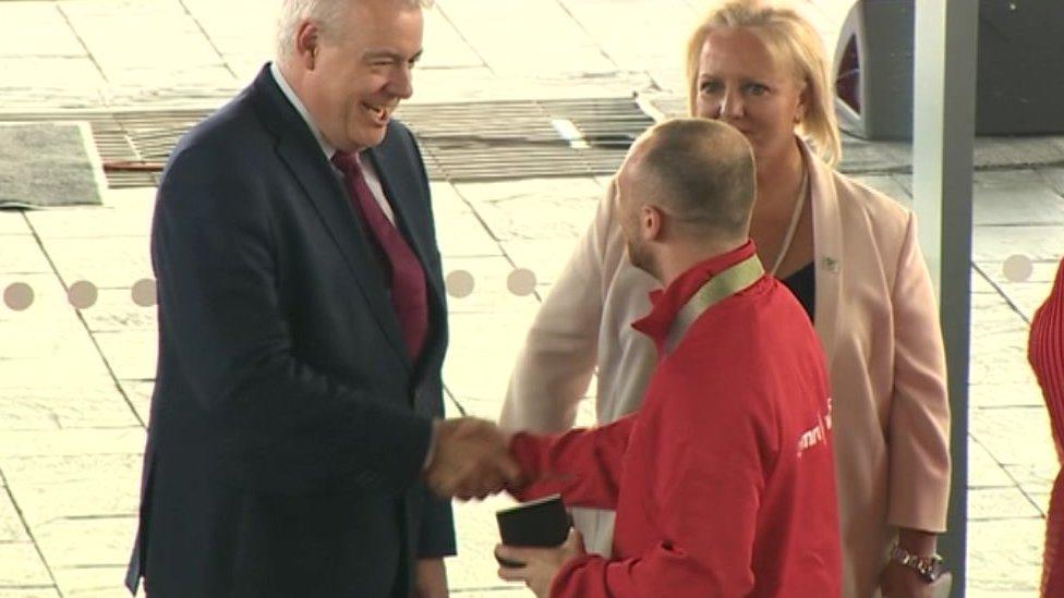 Weightlifter Gareth Evans handed commemorative medal and shakes First Minister Carwyn Jones' hand