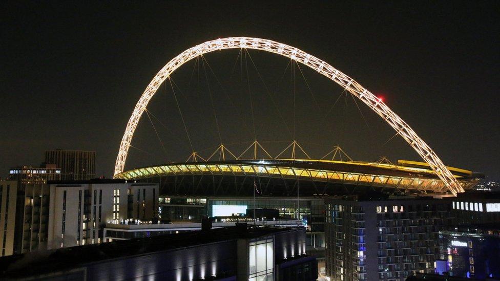 Wembley's famous arch is lit up in yellow.