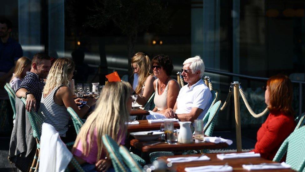 People eating at restaurant tables outdoors