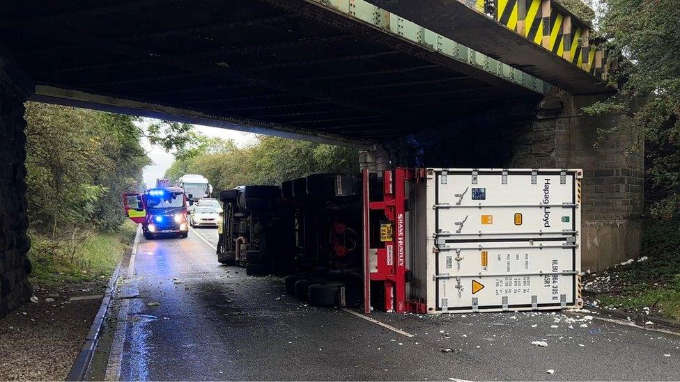 Lorry on its side under bridge