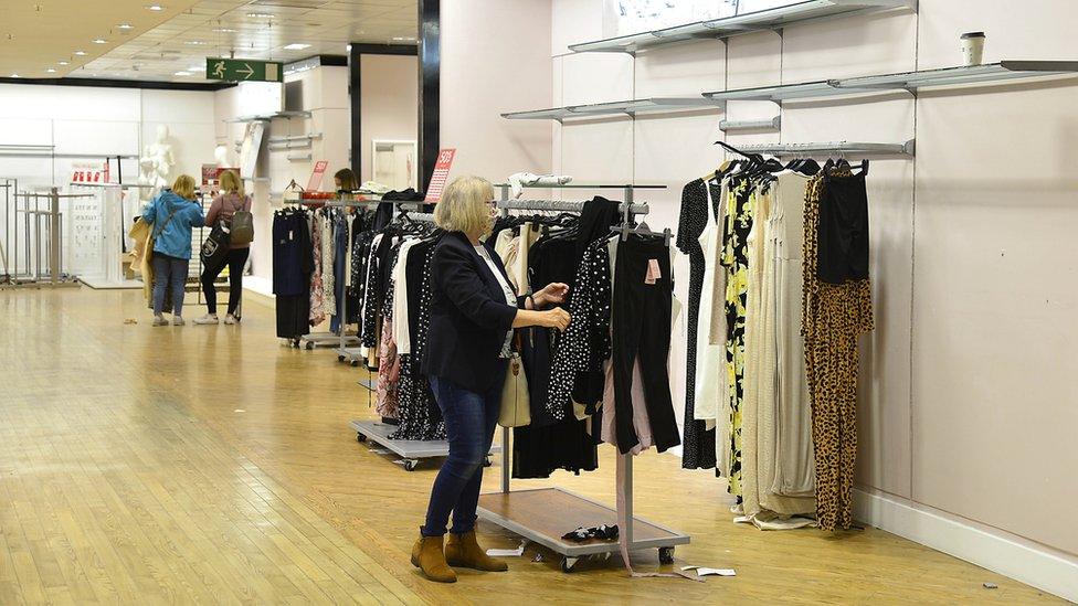 A woman rifles through the last clothes still for sale in a near-empty Debenhams