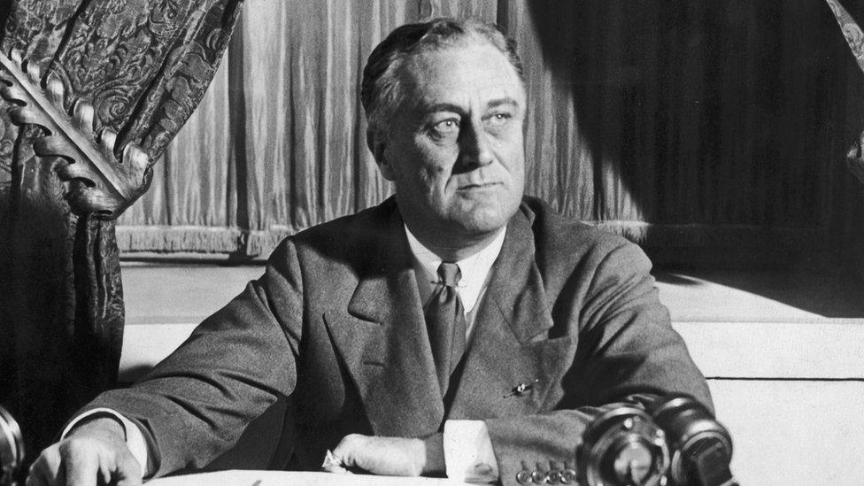 circa 1935: American President Franklin Roosevelt (1882 - 1945) sits at a desk with microphones, probably during a radio broadcast.