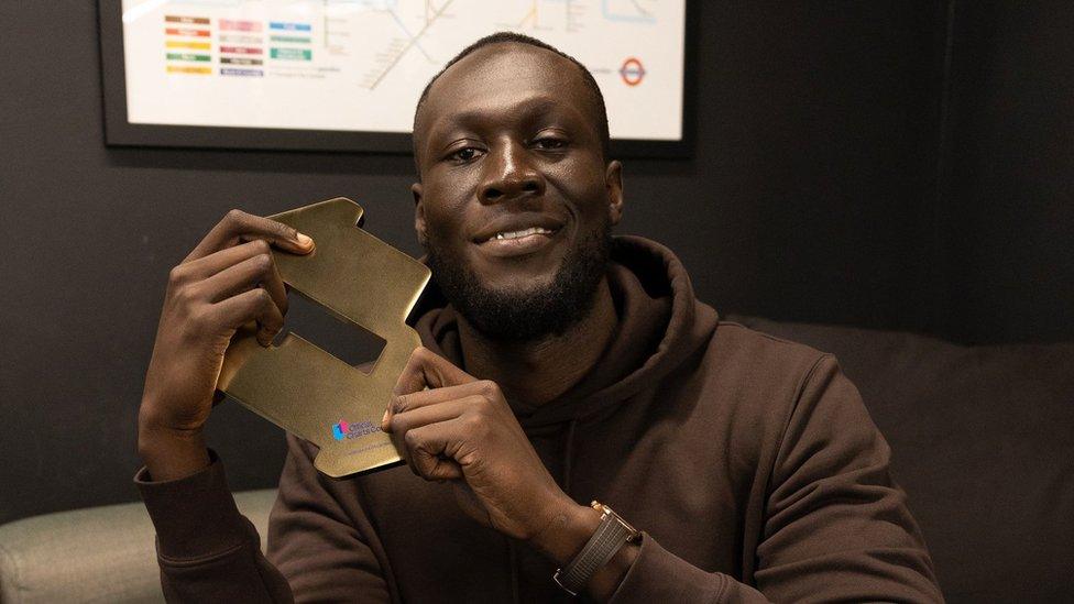 Stormzy holding an Official Charts award