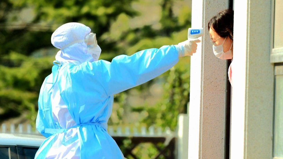 QINGDAO, CHINA - FEBRUARY 03 2020: A government worker checks the temperature of a woman in home quarantine in Qingdao in east China's Shandong province Monday, Feb. 03, 2020.