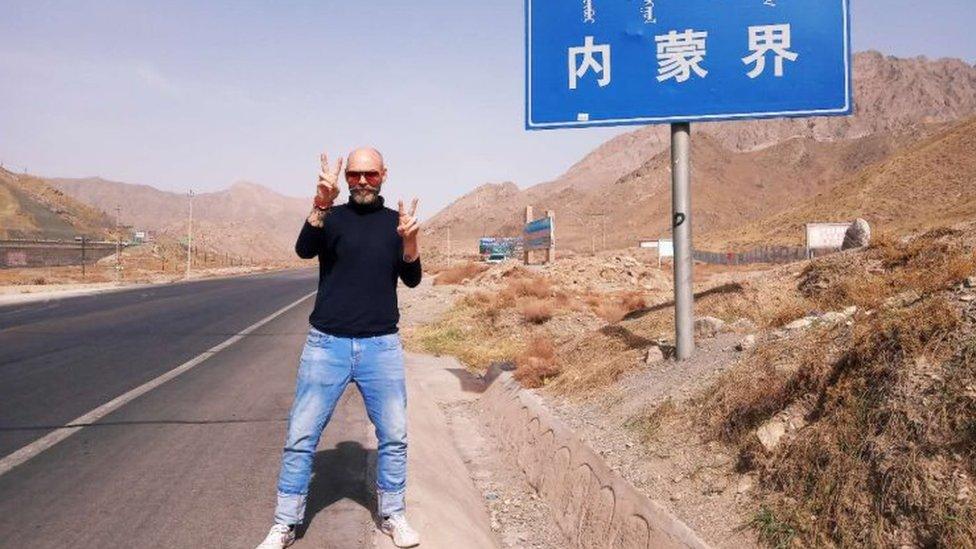 Michael Hope stands beside a Chinese road sign