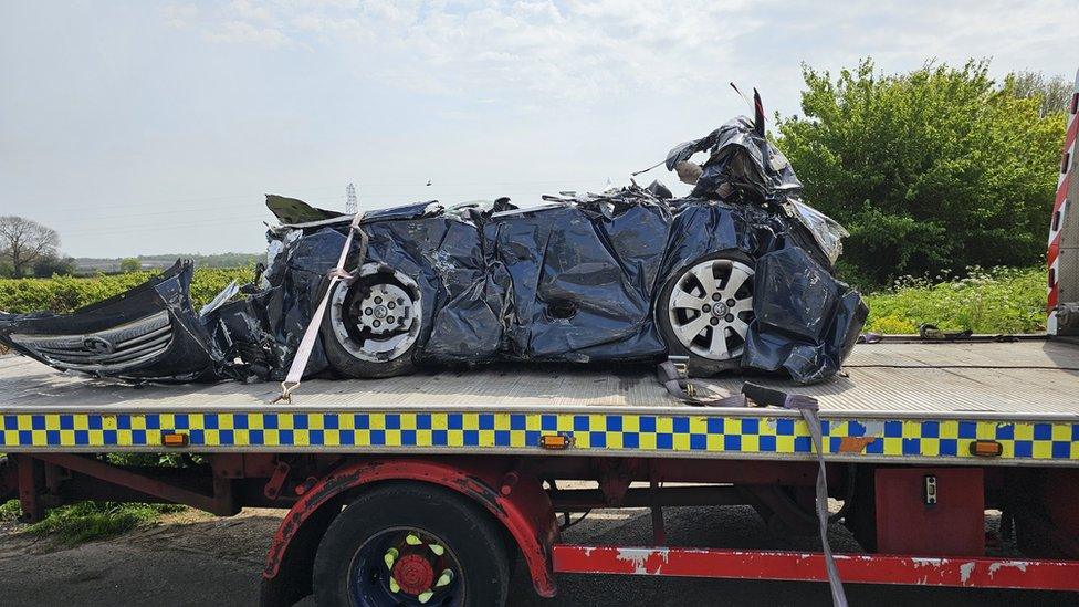 Crushed car on flat bed truck