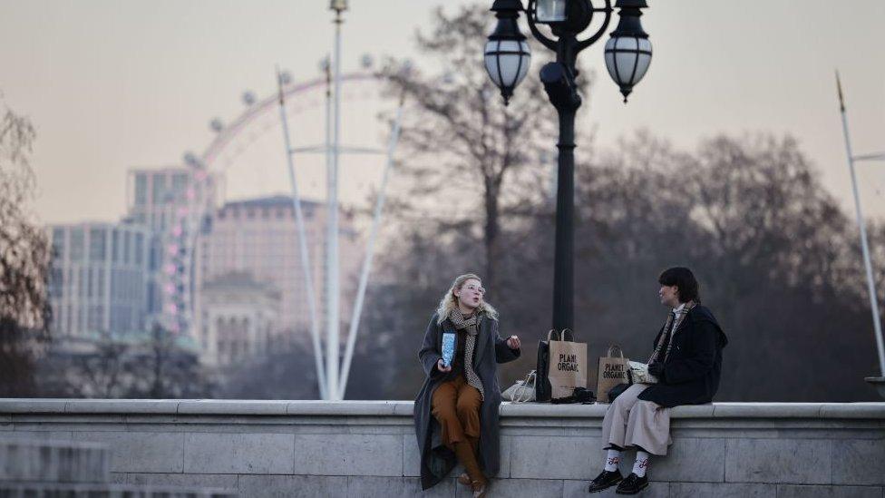 Two people sitting on a wall talking