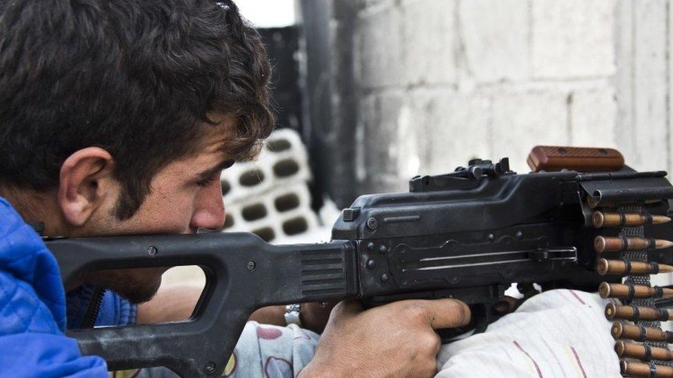 A member of the Kurdish People's Protection Units (YPG) holds a position with his weapon in Kobane (19 November 2014)