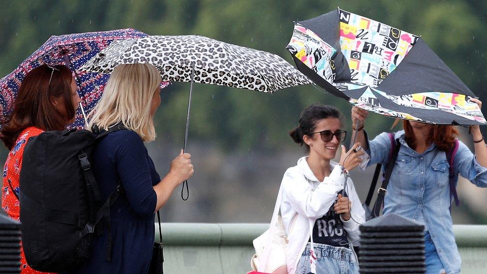 Woman with umbrellas in the rain in central London on 16 August 2022