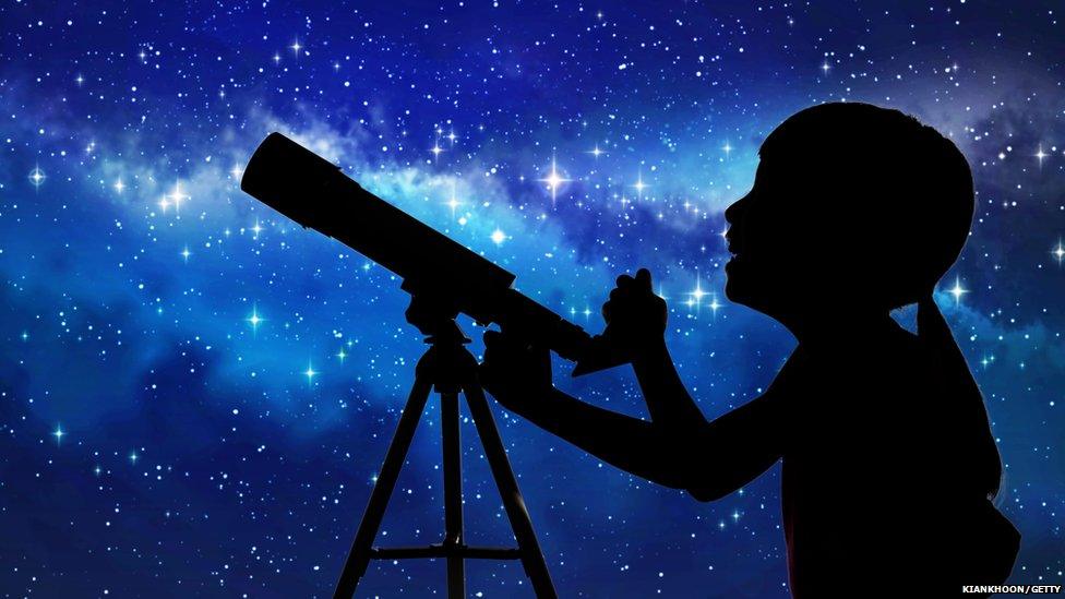 kid looking through a telescope