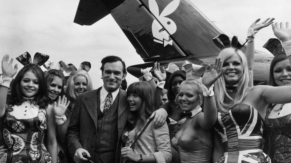 Hugh Hefner and his girlfriend Barbi Benton are welcomed by 'Bunny Girls' from the London Playboy Club, on their arrival at Heathrow Airport aboard his private DC 9 jetliner, which bears the Playboy logo.