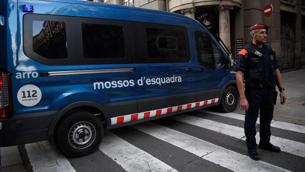 Officer of the Catalan police force stands by a squad van in Barcelona.