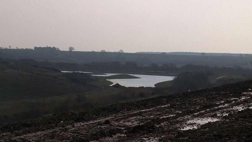 A lake surrounded by mud-covered, undeveloped land.