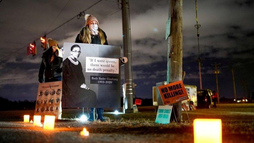 An anti-death penalty activist holds a sign during a vigil outside the United States Penitentiary in Terre Haute, Indiana