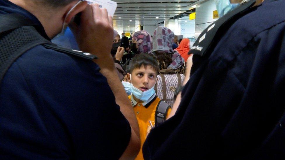 A boy looks on at border force officers