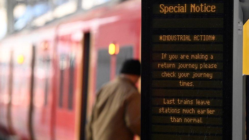 File photo showing man boarding a SWR train with Industrial Action advice displayed on a noticeboard next to him.