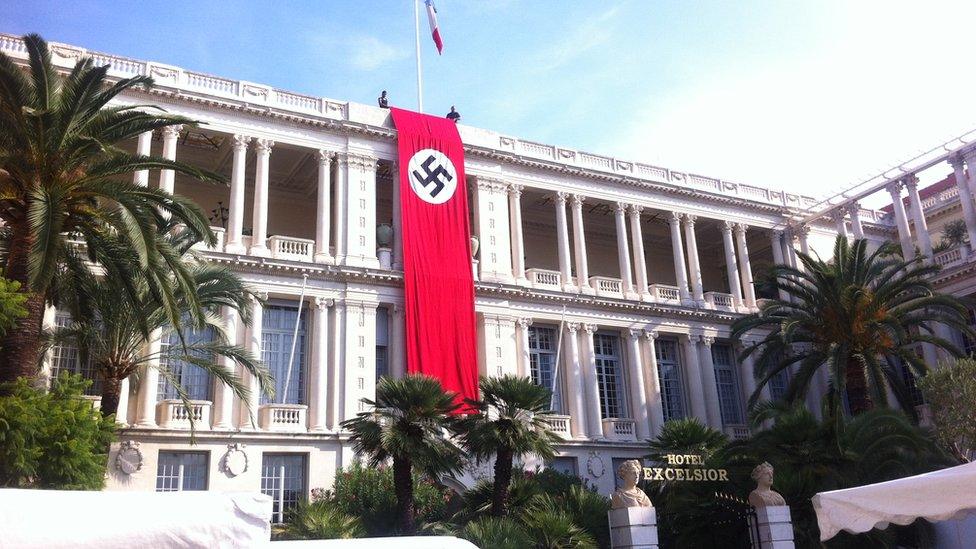 Two men hold Nazi banner over facade of the Palais de la Prefecture in Nice on Monday 28 September