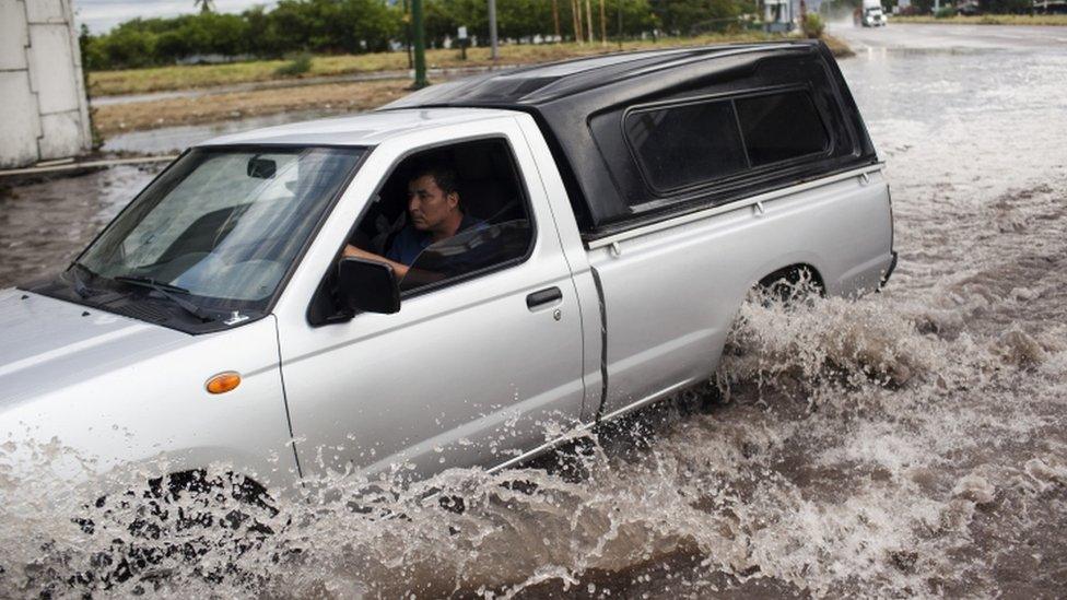 A man drives his truck through flooded streets in Mexico