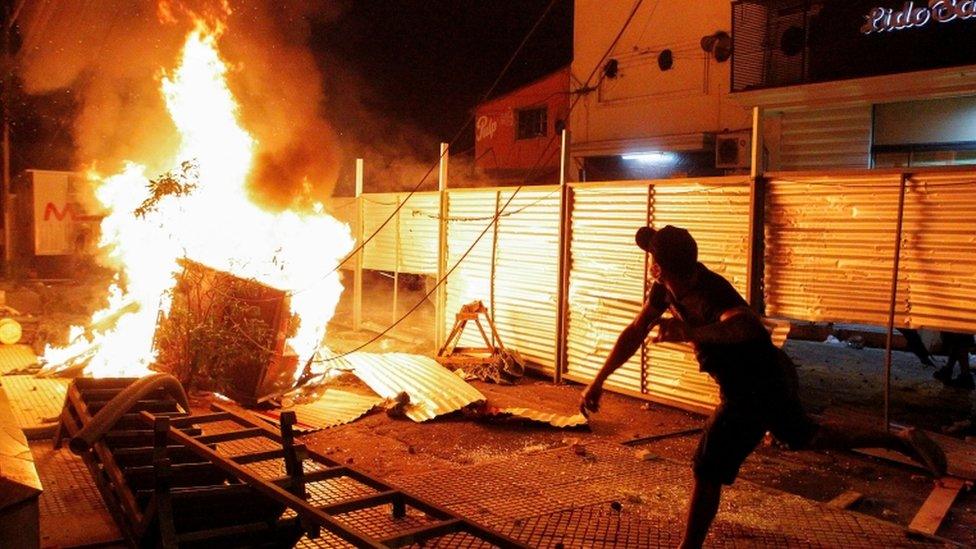 A demonstrator near a fire during a protest against President Mario Abdo Benitez's health policies in Asuncion, Paraguay March 5, 2021