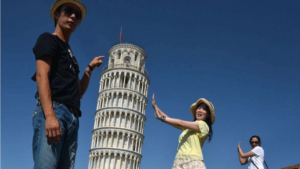 Tourists posing next to the Leaning Tower of Pisa