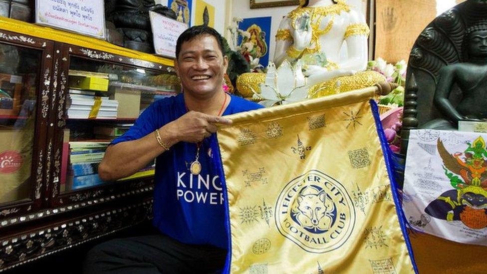 Korpsin Uiamsa-ard, an assistant of chief monk Phra Prommangkalachan at the Wat Traimitr Withayaram temple, holds up a Leicester City banner in Bangkok, Thailand, Tuesday, May 3, 2016