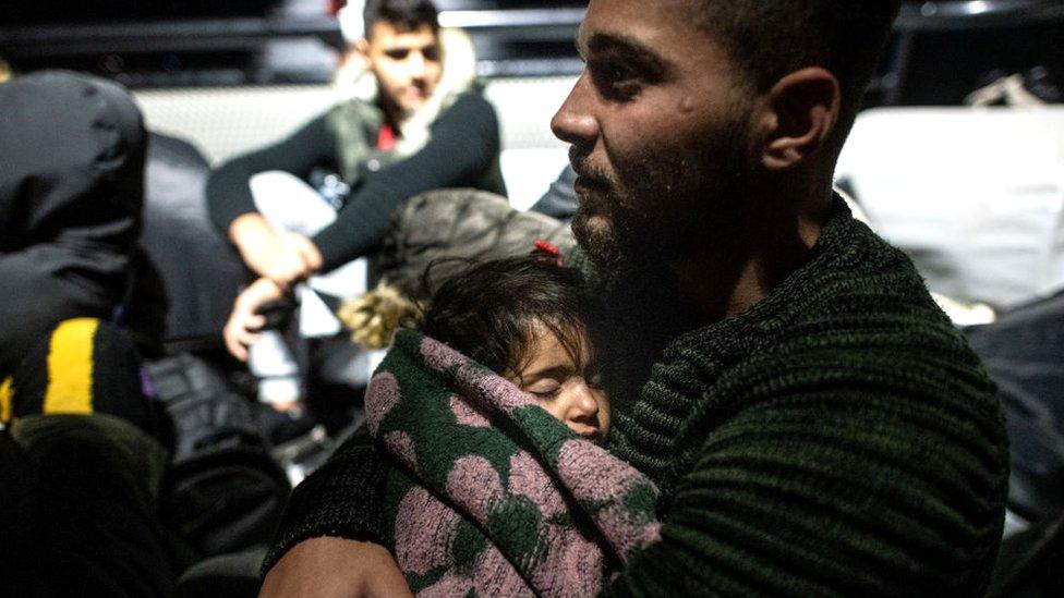 A man embraces a child following a rescue operation on the Aegean sea near the Greek island of Kos, 15 November 2019