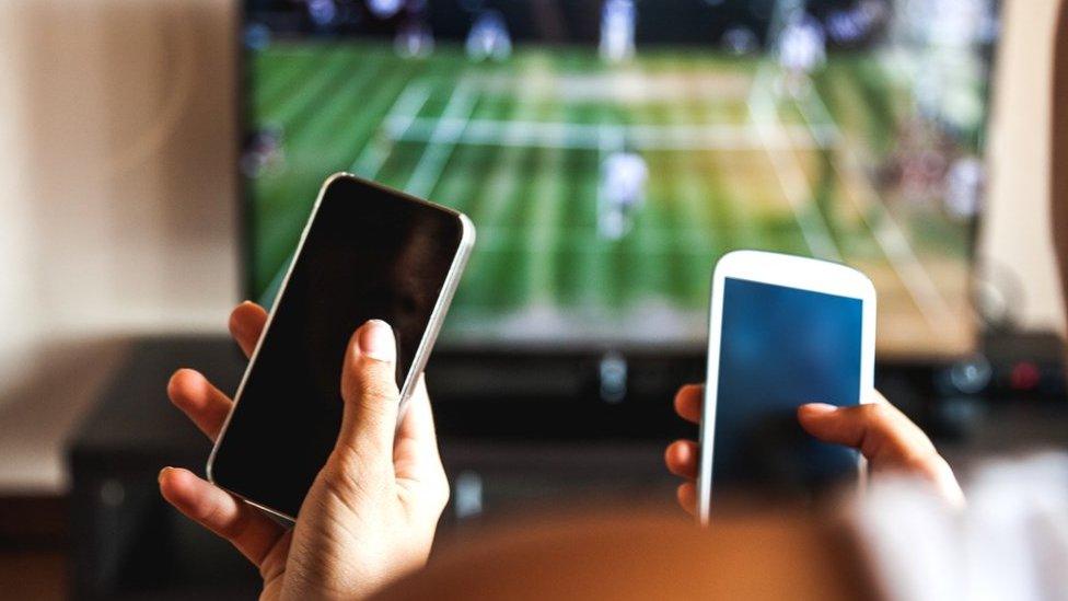 People gambling in front of a tennis match on TV.