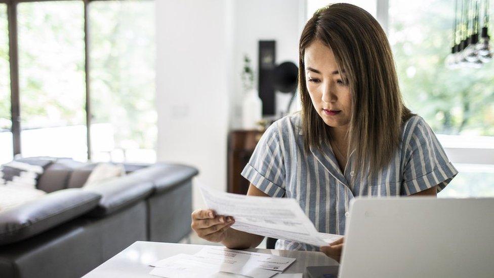 Woman looks at bills - stock shot