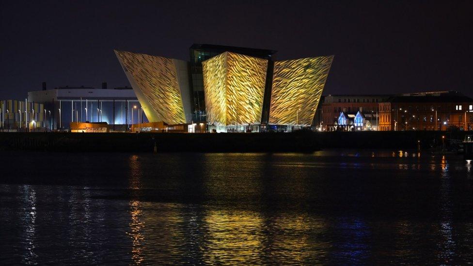 Titanic building and visitor centre in Belfast lit up in yellow.