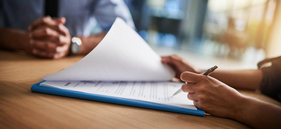 Women filling in form with man watching