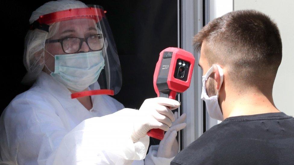 A health worker takes the temperature of a man in Sarajevo