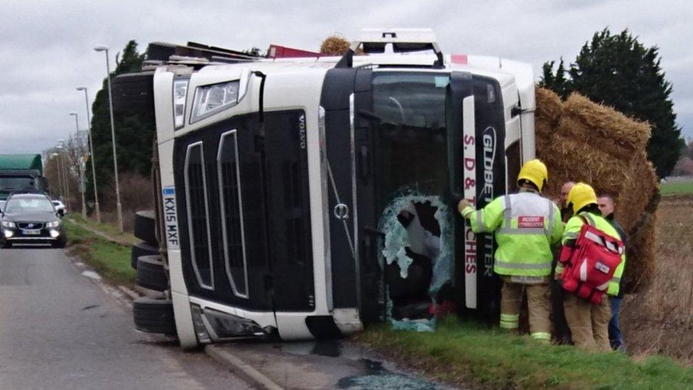 Emergency services attend an overturned lorry with part of its windscreen smashed