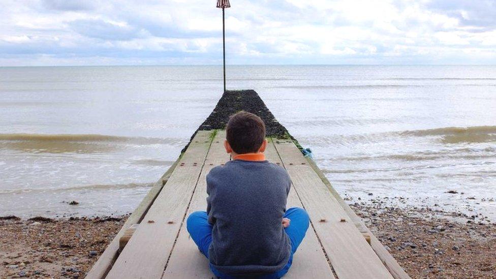 A boy sitting on a jetty