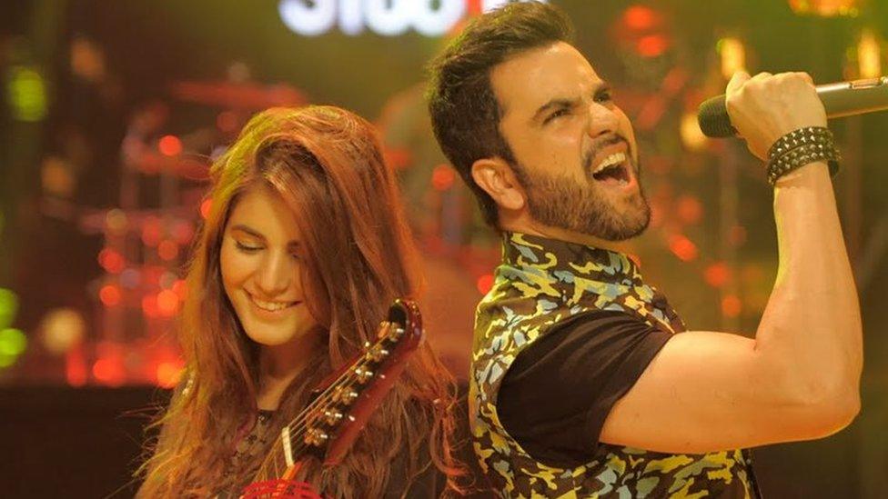 Momina Mustehsan plays guitar next to a male singer on the Coke Studio show