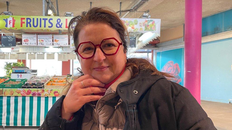 Claire Guichard stands in front of a market stand