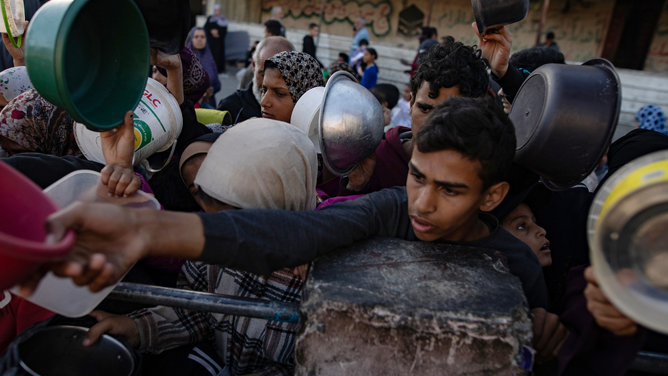 Displaced Palestinians gather to collect food in Rafah on 12 March