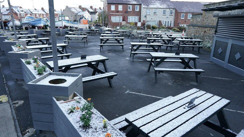 Snow covers benches in a pub beer garden