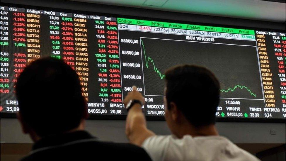 People look at an electronic board at the Sao Paulo Stock Exchange on October 10, 2018