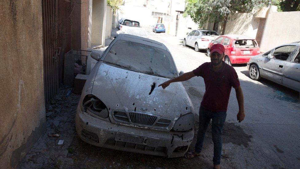 A man looks at a damaged car after rockets fired by unknown militants landed on the residential area of Ben Ashour, Tripoli, on 1 September 2018