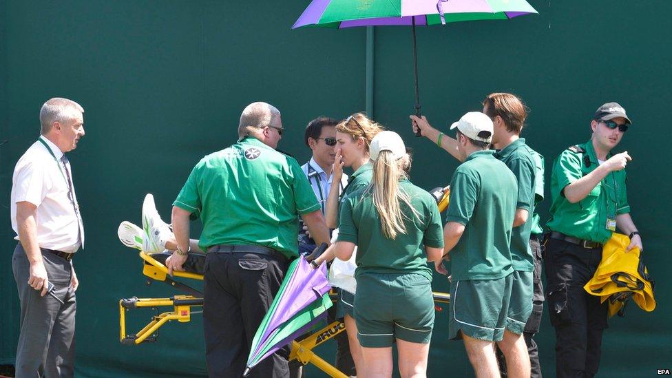 Play is interrupted as medics attend to a ball boy who collapsed at Wimbledon, London, 1 July 2015