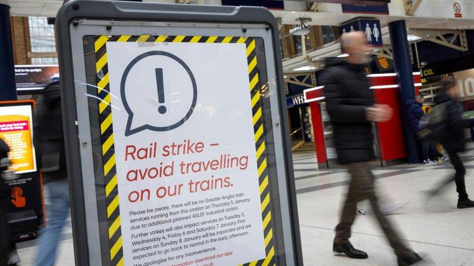 A board informs passengers about rail strikes at Liverpool Station in London