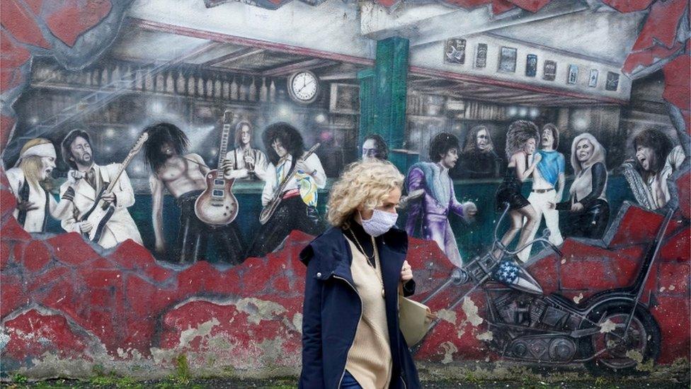 A woman walks past a wall mural during the resurging coronavirus outbreak in Galway, Ireland