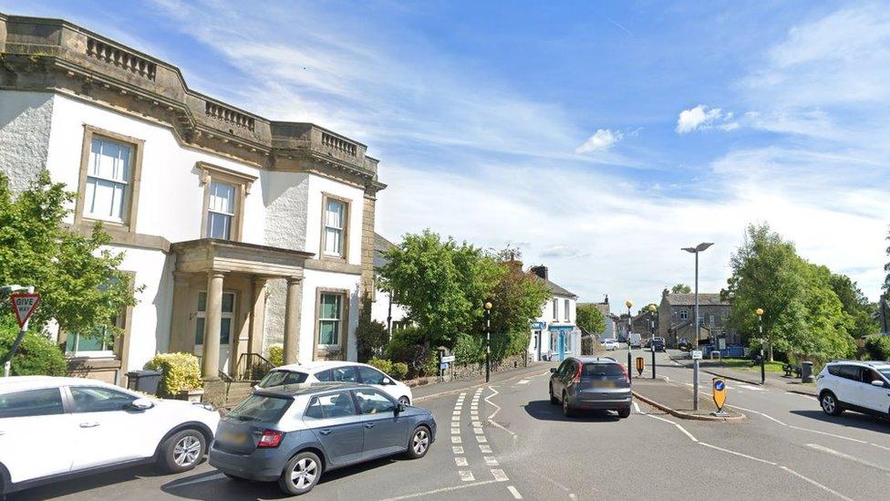 Streetview of cars driving on a road past buildings