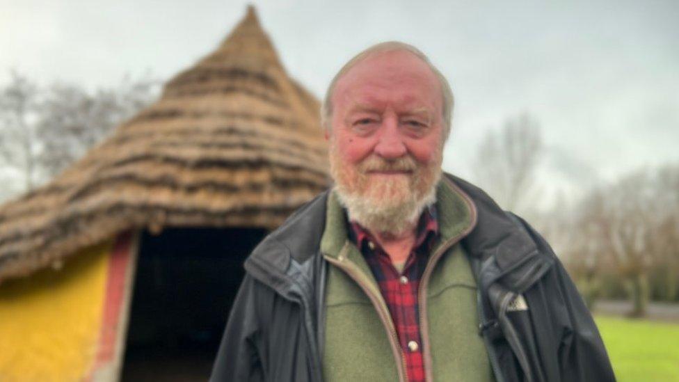 Francis Pryor in front of a roundhouse at Flag Fen