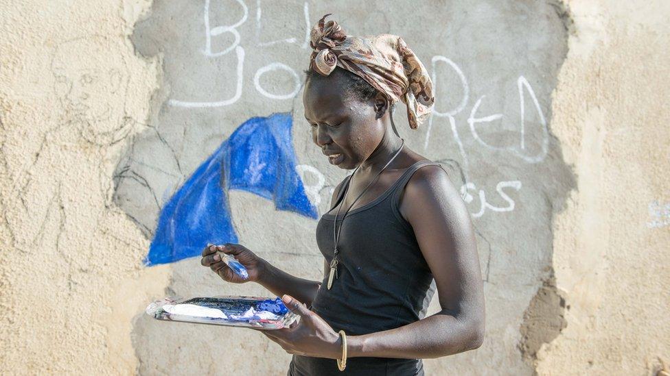 One of the woman artists mixes her blue paint