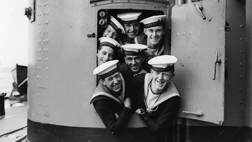 A group of sailors trying to squeeze out of a small door aboard the HMS Hood during naval manoeuvres in 1928