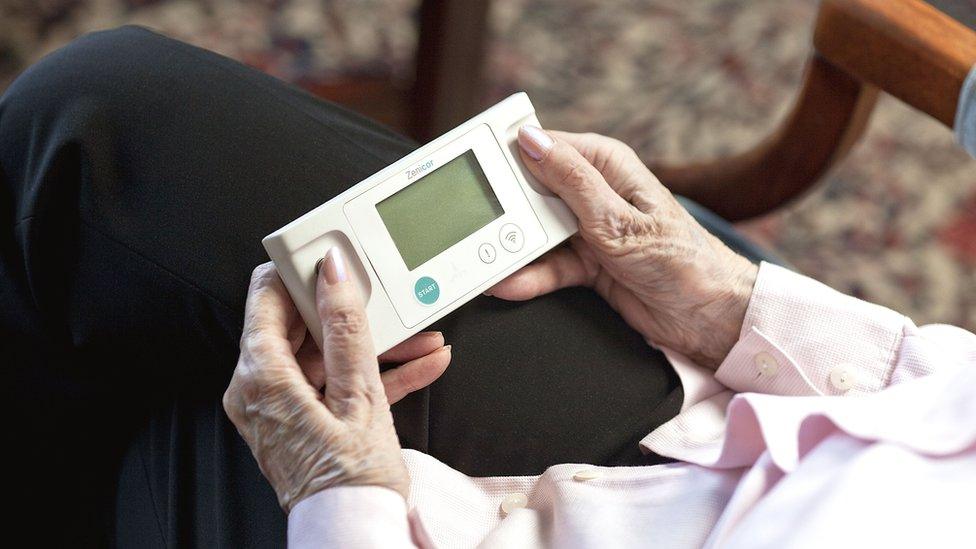 Elderly person using a device to test her heart rhythm