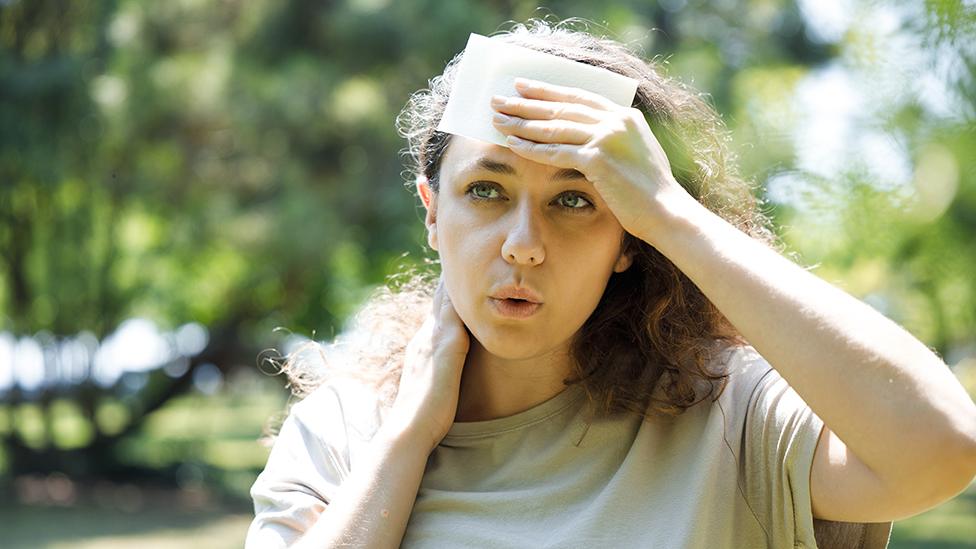 Woman feeling hot in park